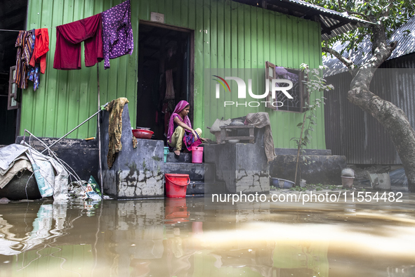 A woman cooks on high ground in front of her flooded house in a village in Chaumuhani Municipality of Noakhali District, Chittagong Division...