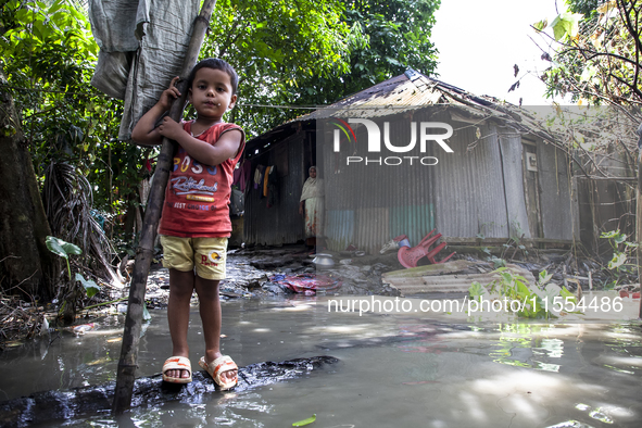 A child and his mother stand in front of their flood-damaged house in a village in Chaumuhani Municipality of Noakhali District, Chittagong...