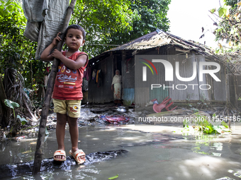 A child and his mother stand in front of their flood-damaged house in a village in Chaumuhani Municipality of Noakhali District, Chittagong...