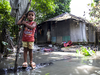 A child and his mother stand in front of their flood-damaged house in a village in Chaumuhani Municipality of Noakhali District, Chittagong...