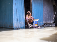 A woman sits in front of her flooded house in a village in Choumuhani Municipality of Noakhali District in Chittagong Division, Bangladesh,...