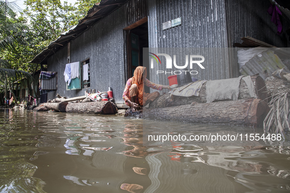 A woman washes necessities in front of her house in the flood water in a village of Chaumuhni Municipality in Noakhali District of Chittagon...