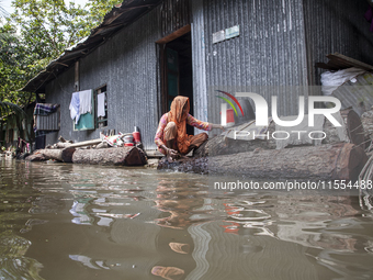 A woman washes necessities in front of her house in the flood water in a village of Chaumuhni Municipality in Noakhali District of Chittagon...