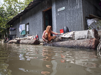 A woman washes necessities in front of her house in the flood water in a village of Chaumuhni Municipality in Noakhali District of Chittagon...