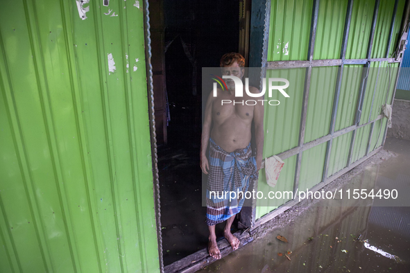 A man stands in front of his flooded house in a village in Chaumuhani Municipality of Noakhali District in Chittagong Division, Bangladesh,...