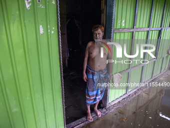 A man stands in front of his flooded house in a village in Chaumuhani Municipality of Noakhali District in Chittagong Division, Bangladesh,...