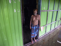 A man stands in front of his flooded house in a village in Chaumuhani Municipality of Noakhali District in Chittagong Division, Bangladesh,...