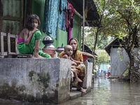 A mother and her children sit in front of their flooded house in a village in Chaumuhani Municipality of Noakhali District in Chittagong Div...