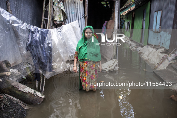 A woman stands in front of her flood-damaged house in a village in Chaumuhani Municipality of Noakhali District in Chittagong Division, Bang...