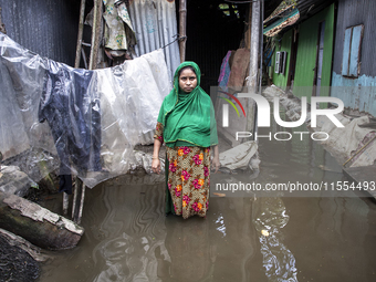 A woman stands in front of her flood-damaged house in a village in Chaumuhani Municipality of Noakhali District in Chittagong Division, Bang...