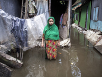 A woman stands in front of her flood-damaged house in a village in Chaumuhani Municipality of Noakhali District in Chittagong Division, Bang...