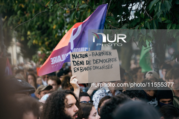 A protestor holds a placard reading, 'Macron-Barnier deni de democratie en bande organisee' as he takes part in a demonstration after the ap...