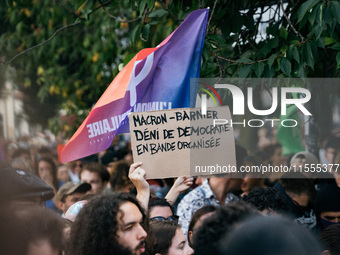 A protestor holds a placard reading, 'Macron-Barnier deni de democratie en bande organisee' as he takes part in a demonstration after the ap...