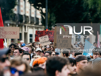 A protestor holds a placard reading, 'Macron arrete de Barnier la voix du peuple' as he takes part in a demonstration after the appointment...