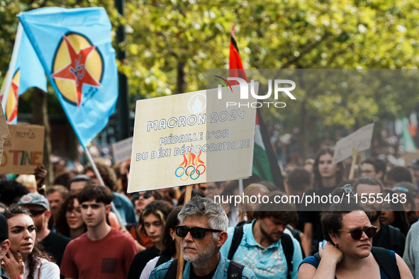 A protestor holds a placard reading, 'Macron 2024, medaille d'or du deni democratique' as he takes part in a demonstration after the appoint...