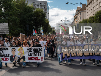 People march holding a banner that reads, 'In the fascist family, I want little Michel' and 'Manu Ciao', during a protest after the appointm...