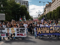 People march holding a banner that reads, 'In the fascist family, I want little Michel' and 'Manu Ciao', during a protest after the appointm...