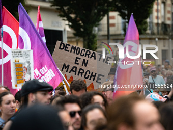 A protestor holds a placard reading, 'democratic en marche' as he takes part in a demonstration after the appointment of a right-wing prime...