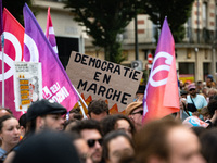 A protestor holds a placard reading, 'democratic en marche' as he takes part in a demonstration after the appointment of a right-wing prime...