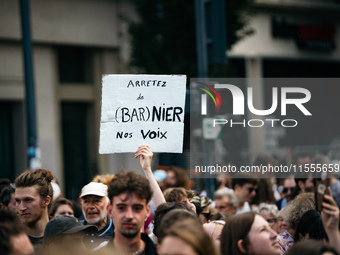 A protestor holds a placard reading, 'arretez de Barnier nos voix' as he takes part in a demonstration after the appointment of a right-wing...