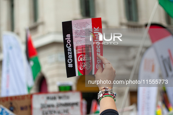 Pro-Palestinian activists and supporters wave Palestinian flags and hold placards, including one depicting a mock ''Gaza Cola'' advertisemen...