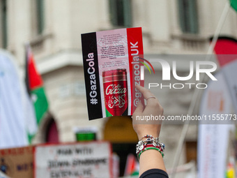 Pro-Palestinian activists and supporters wave Palestinian flags and hold placards, including one depicting a mock ''Gaza Cola'' advertisemen...