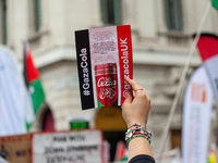 Pro-Palestinian activists and supporters wave Palestinian flags and hold placards, including one depicting a mock ''Gaza Cola'' advertisemen...