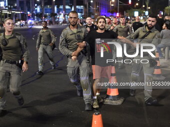 Israeli police detain a protester participating in a protest with thousands of Israelis who protest against the Israeli government, calling...