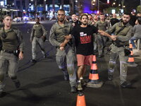 Israeli police detain a protester participating in a protest with thousands of Israelis who protest against the Israeli government, calling...