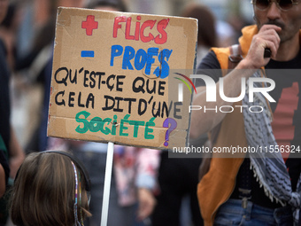 A protester holds a placard reading 'more cops, less profs, what does it say about a society?' Between 5,000 and 8,000 protesters march in T...