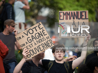 The cardboard on the left reads 'We vote, we win, it's up to us to govern' and the one on the right reads 'Emmanuel to the trash bin'. Betwe...