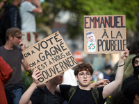 The cardboard on the left reads 'We vote, we win, it's up to us to govern' and the one on the right reads 'Emmanuel to the trash bin'. Betwe...