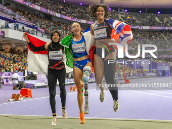 Karisma Tiarani of Indonesia, Martina Caironi of Italy, and Okoh Ndidikama of the UK react after the Women's 100m - T63 Final at Stade de Fr...