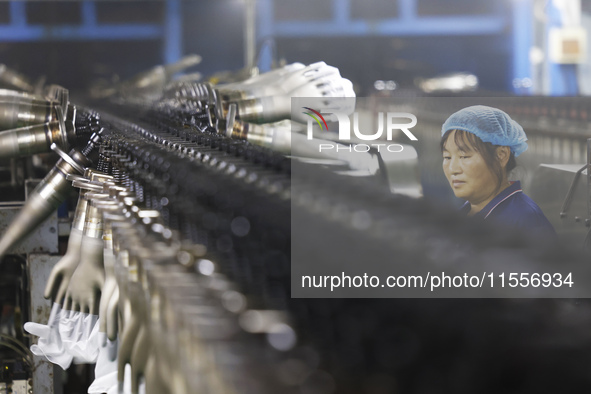 A worker produces disposable PVC gloves for domestic and international markets at a workshop of a foreign-funded enterprise in Suqian, China...