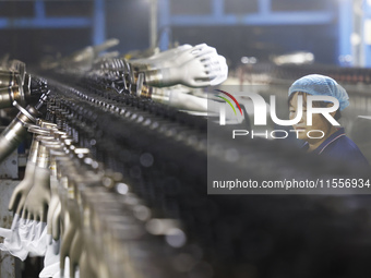 A worker produces disposable PVC gloves for domestic and international markets at a workshop of a foreign-funded enterprise in Suqian, China...