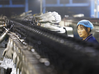 A worker produces disposable PVC gloves for domestic and international markets at a workshop of a foreign-funded enterprise in Suqian, China...