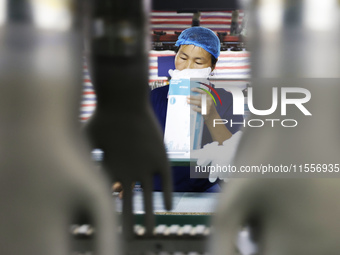 A worker produces disposable PVC gloves for domestic and international markets at a workshop of a foreign-funded enterprise in Suqian, China...