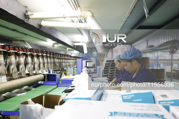 Workers make disposable PVC gloves for domestic and international markets at a production workshop of a foreign-funded enterprise in Suqian,...