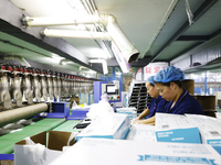 Workers make disposable PVC gloves for domestic and international markets at a production workshop of a foreign-funded enterprise in Suqian,...