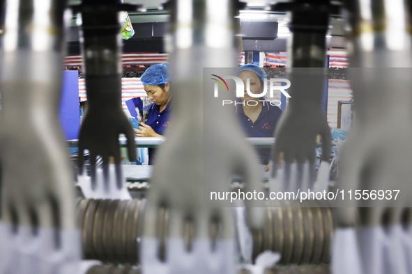 Workers make disposable PVC gloves for domestic and international markets at a production workshop of a foreign-funded enterprise in Suqian,...