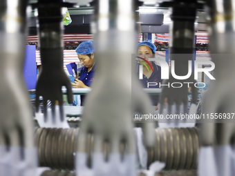 Workers make disposable PVC gloves for domestic and international markets at a production workshop of a foreign-funded enterprise in Suqian,...