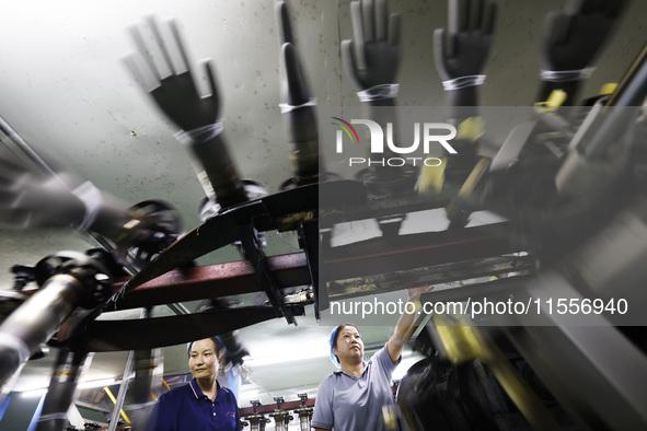 Workers make disposable PVC gloves for domestic and international markets at a production workshop of a foreign-funded enterprise in Suqian,...