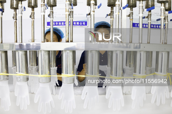 Workers make disposable PVC gloves for domestic and international markets at a production workshop of a foreign-funded enterprise in Suqian,...