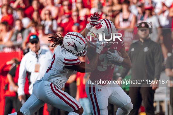 South Dakota defensive back Teven McKelvey #3 grabs the facemask of Wisconsin Badgers running back Jackson Acker #34 at Camp Randall Stadium...