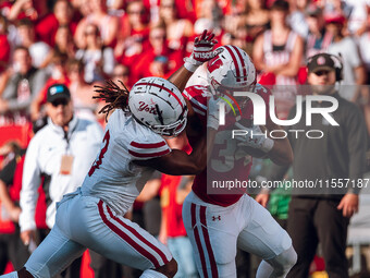 South Dakota defensive back Teven McKelvey #3 grabs the facemask of Wisconsin Badgers running back Jackson Acker #34 at Camp Randall Stadium...