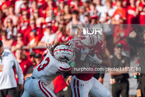 South Dakota defensive back Teven McKelvey #3 grabs the facemask of Wisconsin Badgers running back Jackson Acker #34 at Camp Randall Stadium...