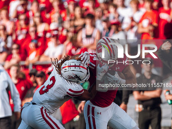 South Dakota defensive back Teven McKelvey #3 grabs the facemask of Wisconsin Badgers running back Jackson Acker #34 at Camp Randall Stadium...