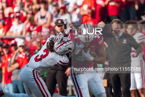 South Dakota defensive back Teven McKelvey #3 grabs the facemask of Wisconsin Badgers running back Jackson Acker #34 at Camp Randall Stadium...