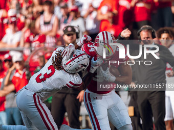 South Dakota defensive back Teven McKelvey #3 grabs the facemask of Wisconsin Badgers running back Jackson Acker #34 at Camp Randall Stadium...