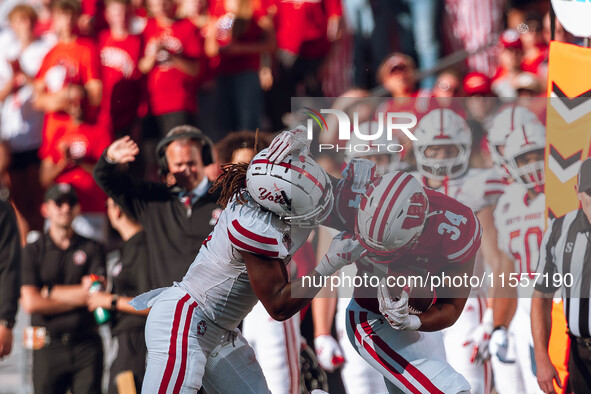 South Dakota defensive back Teven McKelvey #3 grabs the facemask of Wisconsin Badgers running back Jackson Acker #34 at Camp Randall Stadium...